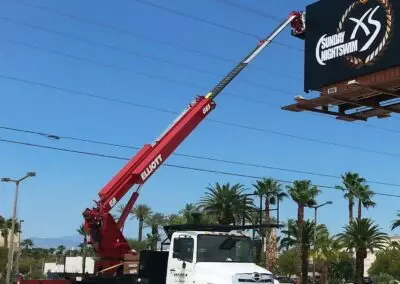 red g 85 truck reaching up to a billboard