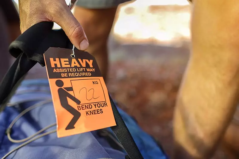 person lifting large back with heavy warning tag